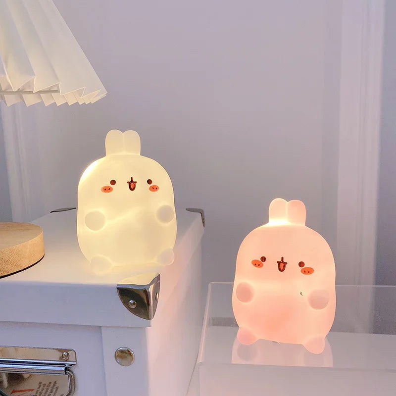 Two cartoon-style night lights on a surface with a neutral background